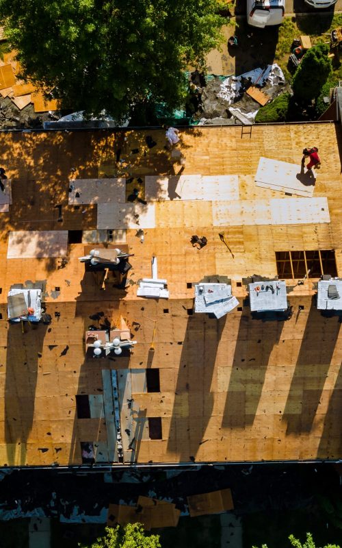 A worker replace shingles on the roof of a home repairing the roof of a home